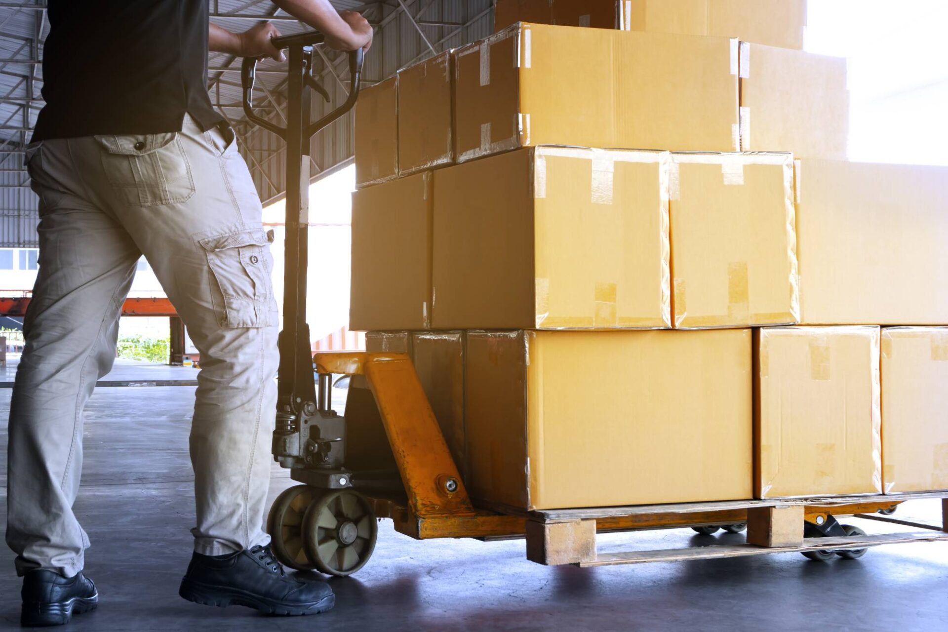 Warehouse worker working with hand pallet truck, stack package boxes on wooden pallet, cargo shipment transport and logistics
